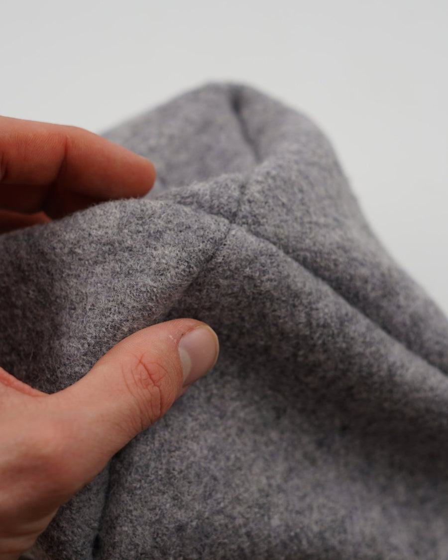 Die flache Saunamütze aus Wollwalk in der Hand